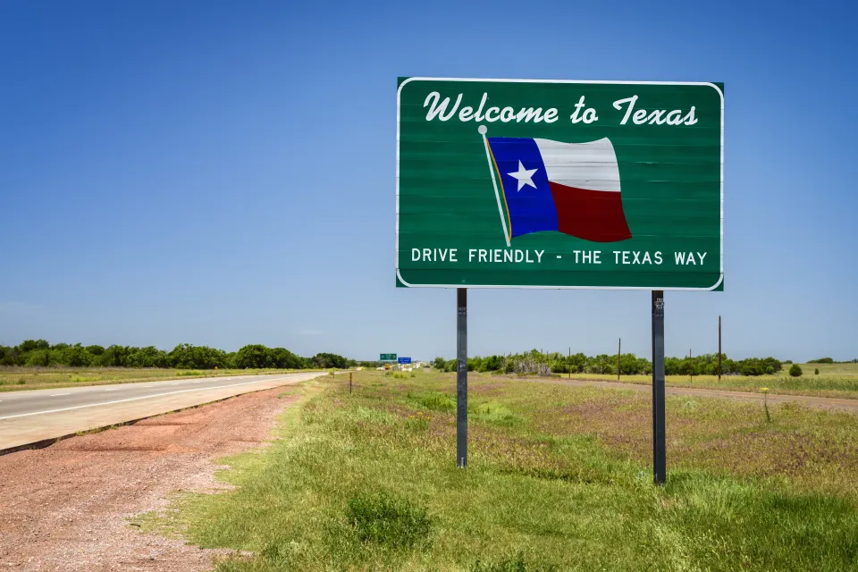 "Welcome to Texas" road sign with Texas flag and "Drive Friendly - the Texas way" slogan
